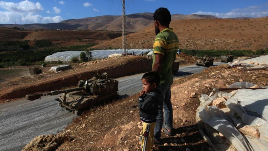 A Palestinian farmer and his son watch Israeli troops making their way through Palestinian farms during a military exercise near Jeftlik in the Jordan valley. Photograph: Alaa Badarneh/EPA