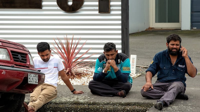 Grieving members of the public sit on a curb following a shooting resulting in multiple fatalities and injuries at the Masjid Al Noor mosque in Christchurch. Photograph: Martin Hunter/PA