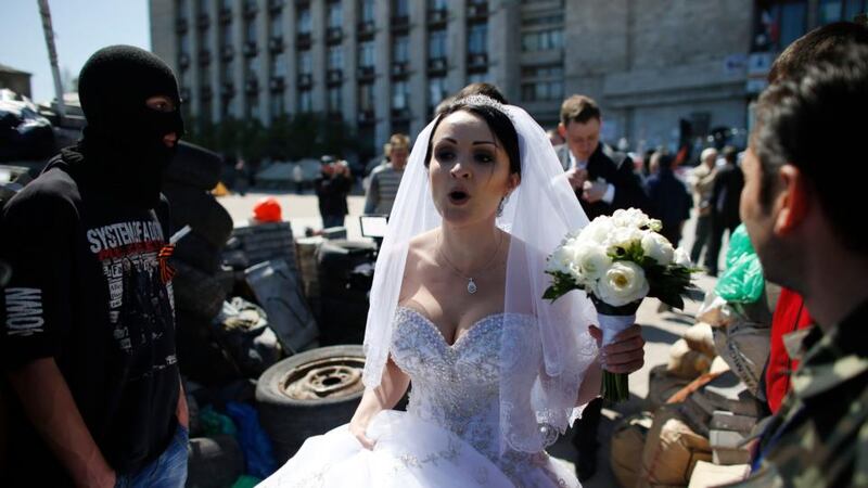 A bride passes by a masked pro-Russia activist near a barricade outside a regional government building in Donetsk, in eastern Ukraine. Photograph: Marko Djurica/Reuters