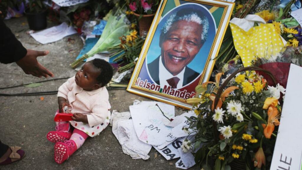 A little girl has her photograph taken as she and her family pay tribute to Nelson Mandela at the memorial wall near the Medi-Clinic Heart Hospital. Photograph: Christopher Furlong/Getty Images
