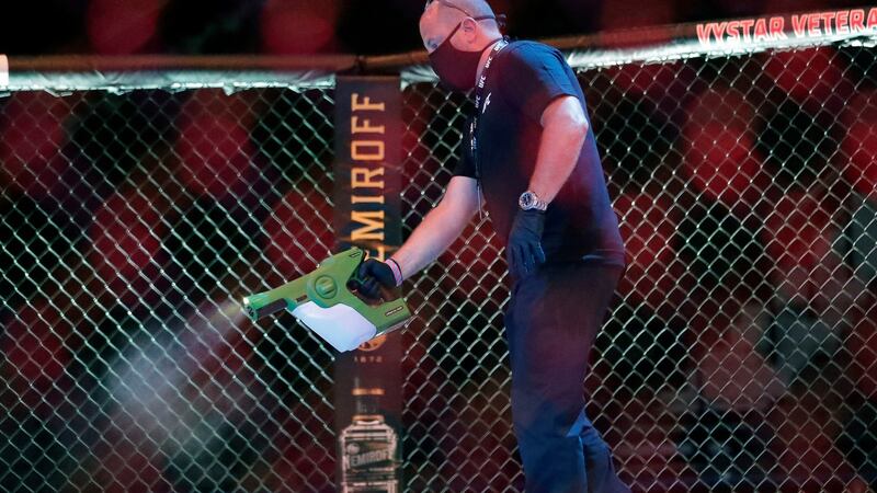 A worker sprays sanitiser in the octagon between bouts. Photograph: AP