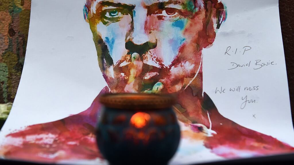 A candle in front of a painting of  David Bowie in Brixton, London, after his death was announced. Photograph: Andy Rain/EPA