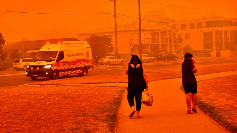 A fire and rescue van drives past people walking along a road shrouded in smoke in Batemans Bay, New South Wales. Photograph: Mark Graham/Bloomberg.