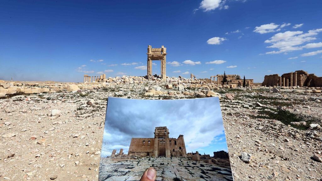 A general view taken in March shows a photographer holding his picture of the Temple of Bel taken in 2014 in front of the remains of the historic temple after it was destroyed by the Islamic Statein September 2015. Photograph: Joseph Eid/Getty