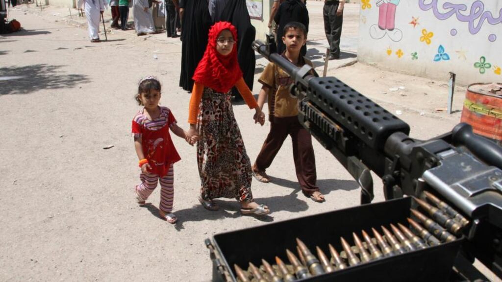 Children walk by a machinegun post near election centre in Baghdad today. Photograph: Wissm al-Okili/Reuters