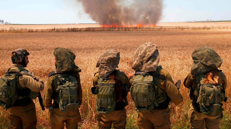 Israeli soldiers walk watch smoke from a fire in a wheat field near the Kibbutz of Nahal Oz in Israel, along the border with the Gaza Strip on Monday. Photograph: Jack Guez/AFP/Getty Images