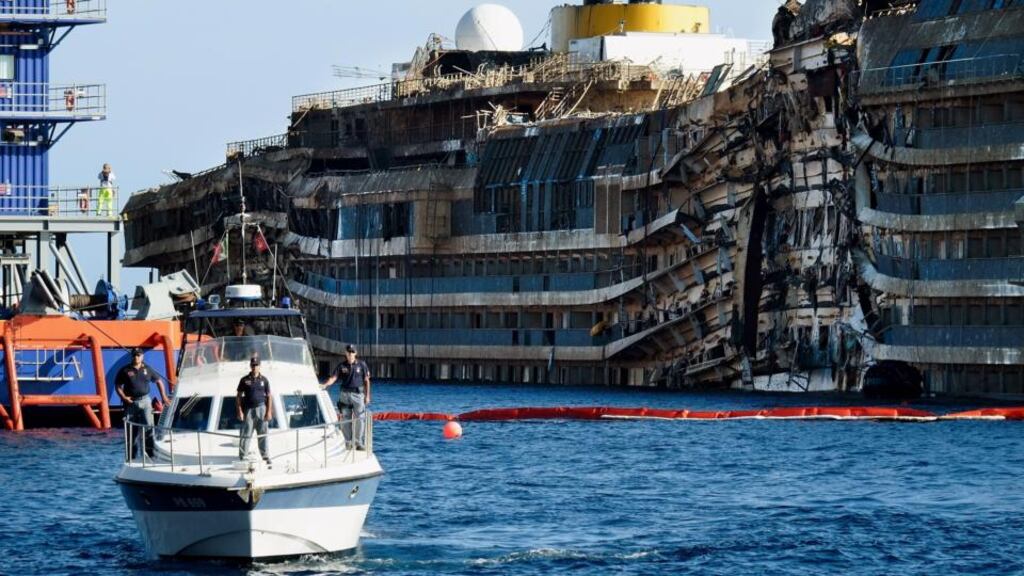 A police boat patrols in front of the severely damaged right side of the Costa Concordia cruise ship in Isola del Giglio, Italy. Photograph: Getty