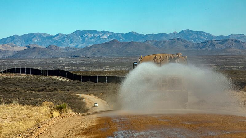 A truck sprays water over a road along a stretch of the border wall in the San Bernardino Valley of Arizona: There was a last-minute rush to build during Trump’s last days in office. Photograph: Adriana Zehbrauskas