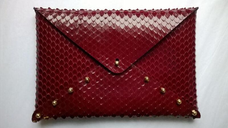 A red snakeskin style clutch in calfskin with brass fitting by Una Burke