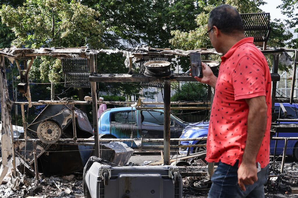 A man takes photos of burnt out cars and debris on avenue Pablo Picasso following a night of civil unrest in Nanterre, near Paris. The violence broke out after police fatally shot a 17-year-old during a traffic stop in Nanterre. Photograph: Mohammed Badra/EPA