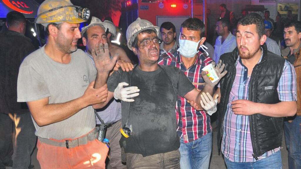 Miners escort a rescued colleague after the explosion and fire at a coal mine in Soma in western Turkey yesterday. Photograph: AP Photo/IHA