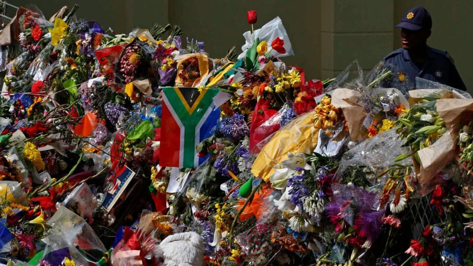A police officer stands behind fences covered by flowers outside the house where former South African President Nelson Mandela died, in Johannesburg, December. Photograph: Yves Herman/Reuters
