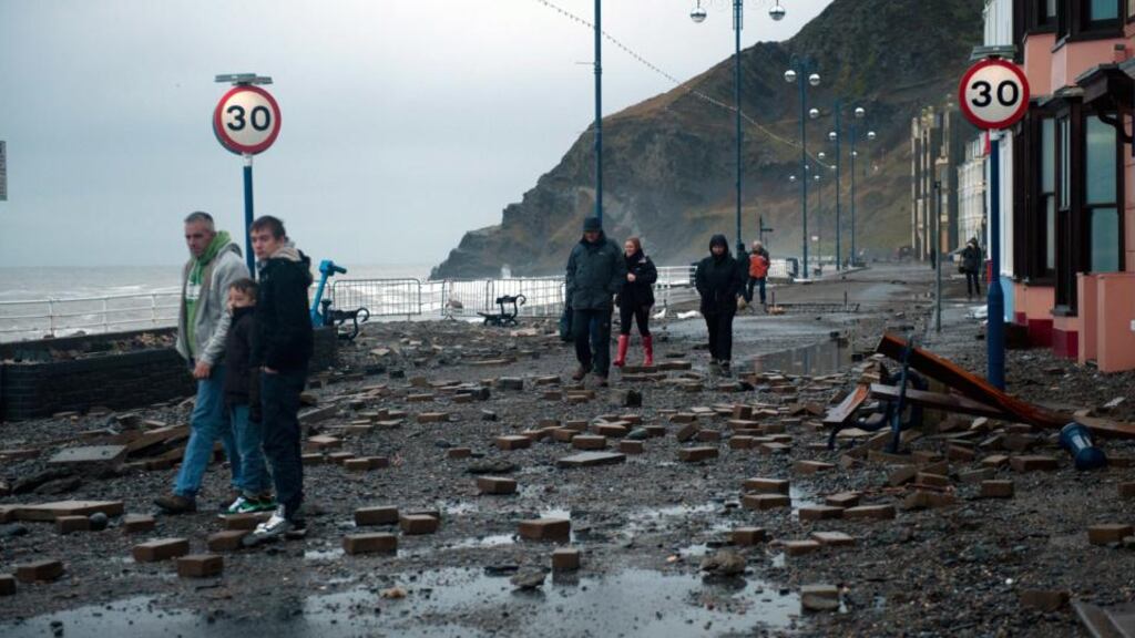 Locals walk through the debris-ridden promenade in Aberystwyth, West Wales, after taking a battering from waves driven by storm-force winds. Photograph: EPA/Dimitris Legakis