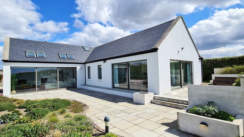 The house features floor-to-ceiling windows and a large outdoor terrace