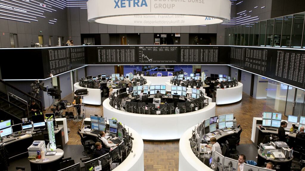Financial traders work at their desks underneath a display of the DAX Index curve at the Frankfurt Stock Exchang. Photograph: Hannelore Foerster/Bloomberg