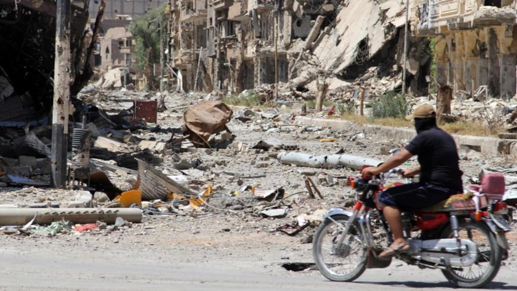A Free Syrian Army fighter rides a motorbike along a damaged street filled with debris in Deir al-Zor, Syria, yesterday. Photograph: Karam Jamal/Reuters