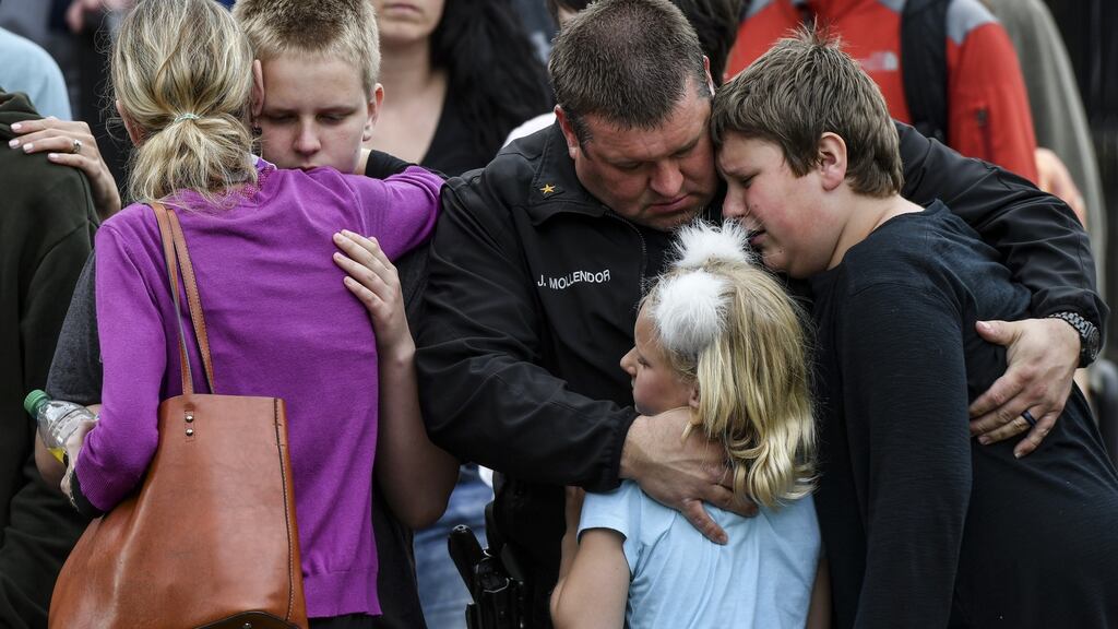 A police officer hugs his kids after they were evacuated to a centre after a shooting at school in Colorado. Photograph: Michael Ciaglo/Getty Images