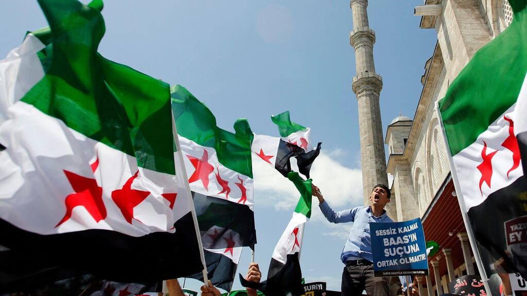 Demonstrators shout Islamic slogans as they wave Syrian opposition flags during a protest against Syria’s president Bashar al-Assad at the courtyard of Fatih mosque in Istanbul yesterday. The sign reads: “Being silent means to be take part in the crime of Baath.” Photograph: Murad Sezer/Reuters
