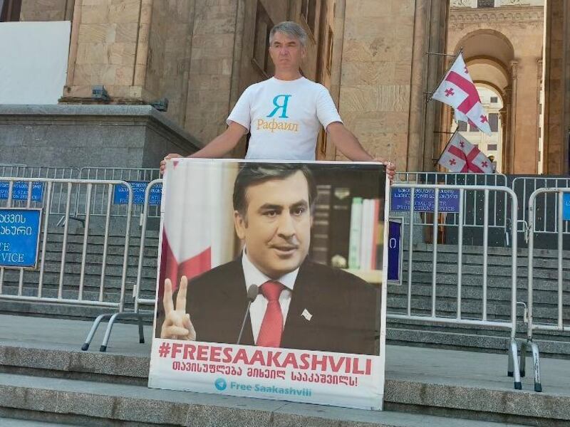 Rafail Shepelev holds a placard outside Georgia's parliament calling for the release of former Georgian president Mikheil Saakashvili