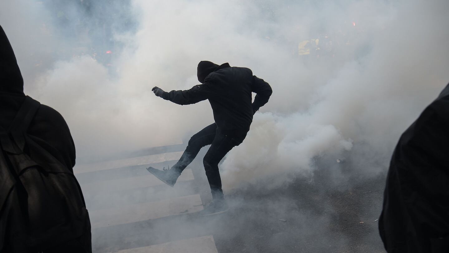 A masked protester kicks a tear gas canister back towards police in Paris. Photograph: Lucas Barioulet/AFP/Getty
