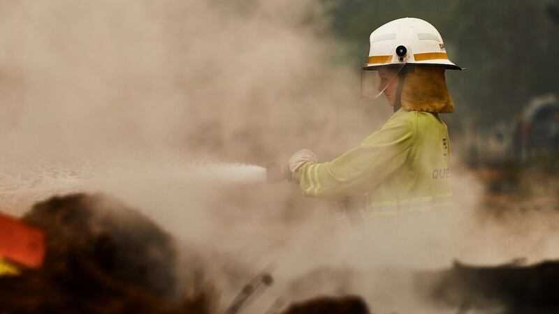 Fire Rescue Queensland crews work to put out smouldering fires in Wingello, Australia, on Sunday.