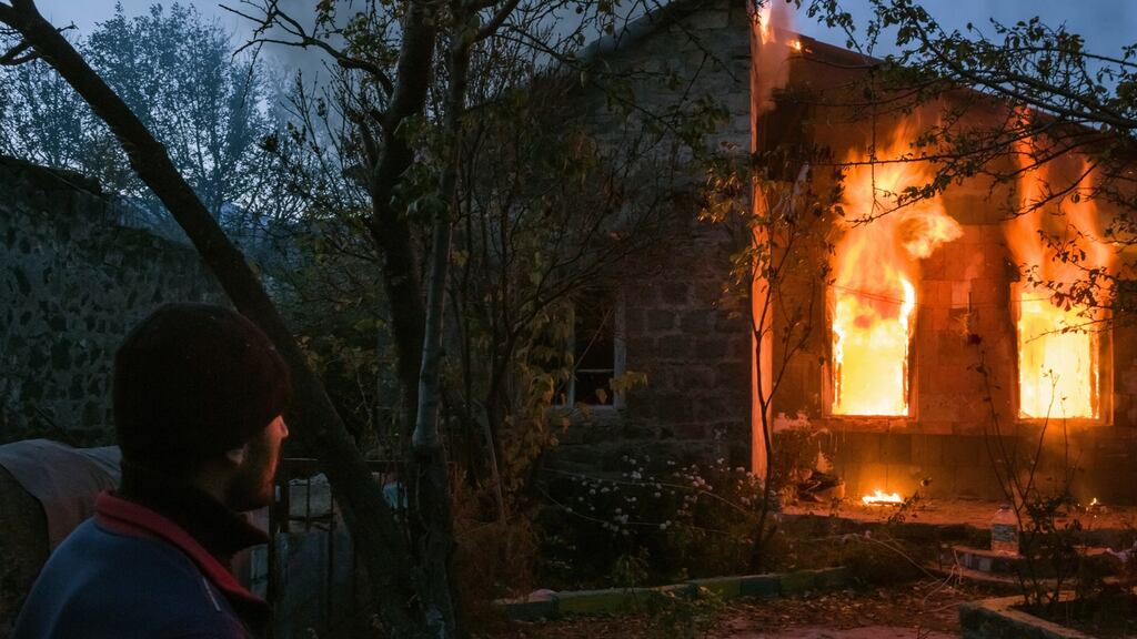 A resident watches a home set on fire by residents preparing to leave the Kelbajar District, before Azeris arrive to take over. Photograph: Mauricio Lima/New York Times