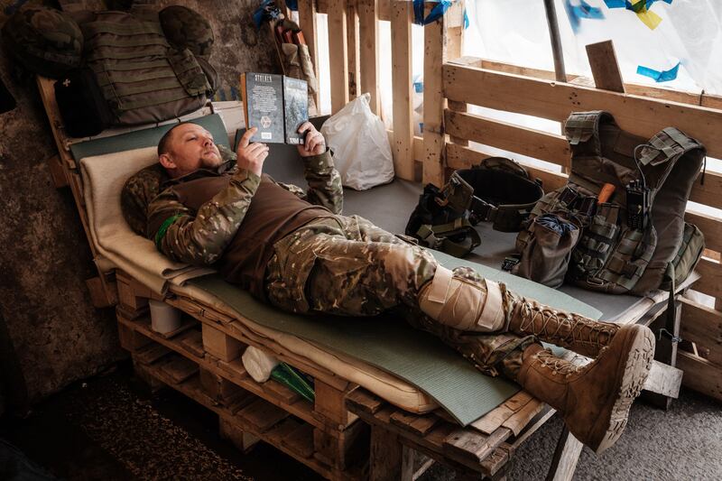 A Ukrainian soldier reads a book as he rests at a checkpoint in Bakhmut, eastern Ukraine, in April 2022. The city was occupied by the Russians the following year. Photograph: Yasuyoshi Chiba/AFP/Getty