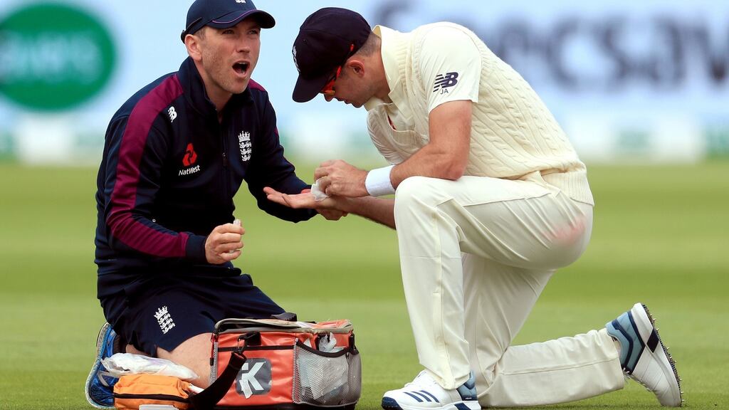 England’s James Anderson (right) receives treatment on his hand during day one of the Ashes Test match at Edgbaston, Birmingham. Photo: Mike Egerton/PA Wire