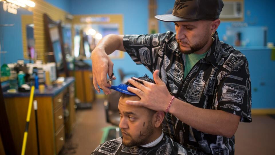 Barbershop owner Hasan Khalil cuts the hair of Amer Daher, a Yazidi, in Lincoln. For the past year, the Yazidi community of Lincoln have watched as Islamic State militants ransacked their ancestral villages and murdered hundreds of their people. Photograph: Andrew Dickinson/The New York Times