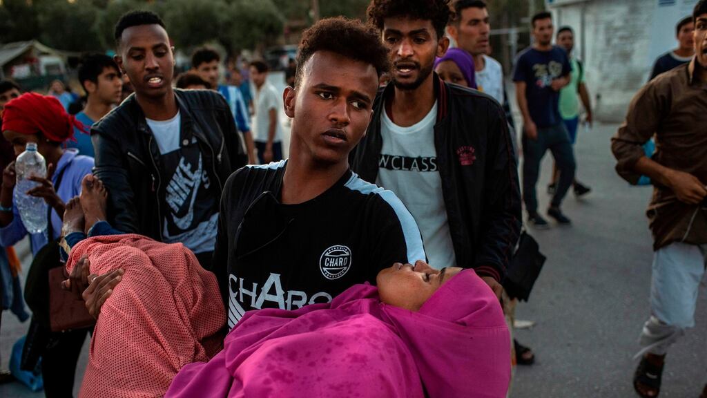 A migrant carries a woman during clashes with police outside the refugee camp of Moria on the Greek island of Lesbos on Sunday. Photograph: Angelos Tzortzinis/Getty Images