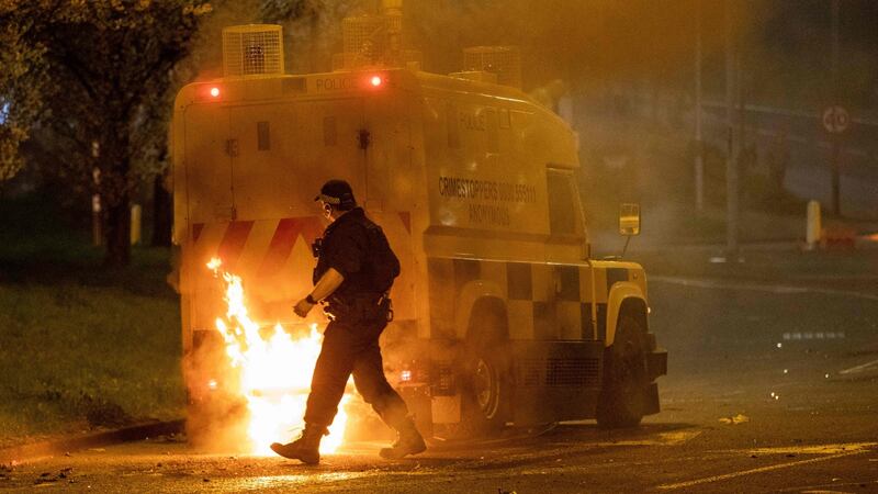 A PSNI officer walks behind a police vehicle engulfed in flames following violence in Newtownabbey, Belfast. Photograph: Paul Faith/AFP via Getty