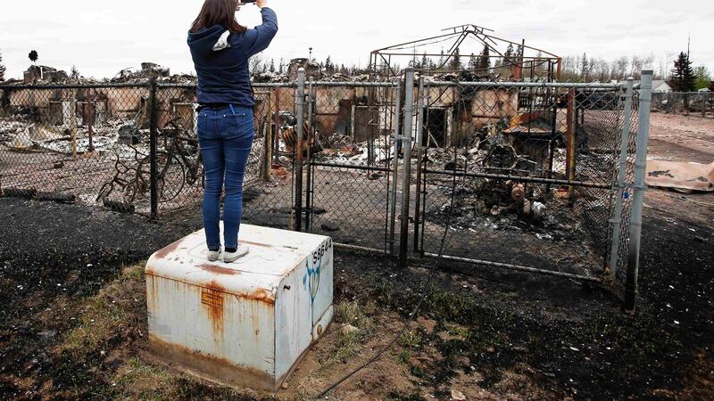 A woman takes photos of the burned remains of a house in the Abasand neighbourhood of Fort McMurray, Alberta, Canada. Photograph: Chris Wattie/Reuters