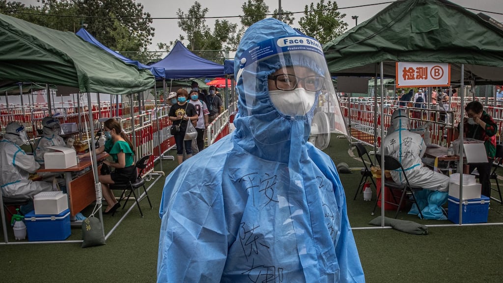 A worker wearing a full protective suit stands as people are tested for Covid-19 at a makeshift coronavirus testing centre, in Beijing on Wednesday. Photograph: EPA