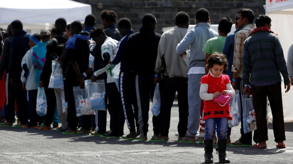 A child plays with a handbag as other migrants queue to be medically checked in Sicily, Italy. Photograph: Darrin Zammit Lupi/Reuters