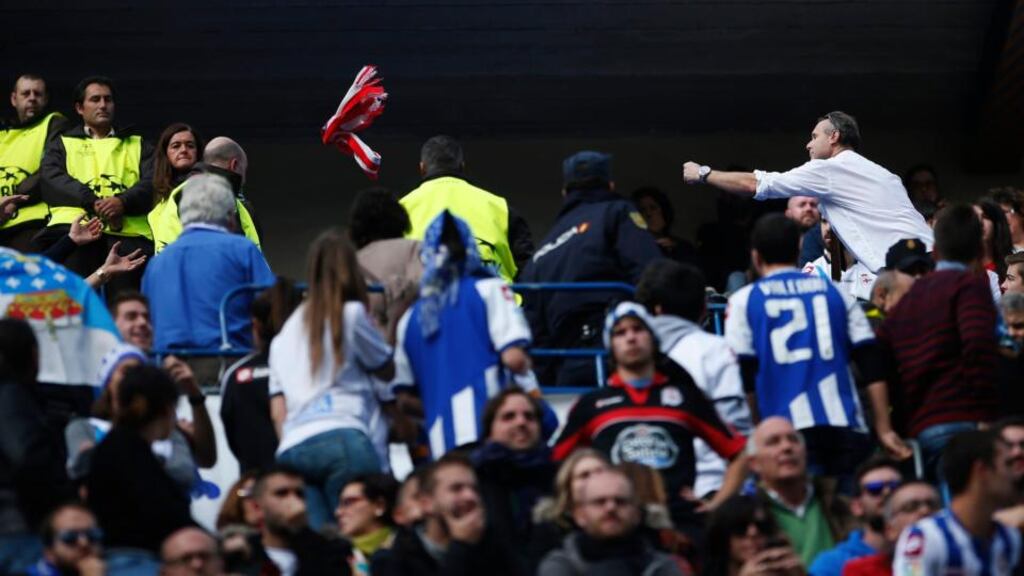 In a mark of solidarity an Atletico Madrid fan  throws his team’s scarf to Deportivo Coruna supporters during their Spanish first division soccer match at Vicente Calderon stadium in Madrid. A Deportivo La Coruna supporter died when dozens of rival fans clashed near the stadium before the game. Photograph: Susana Vera/Reuters