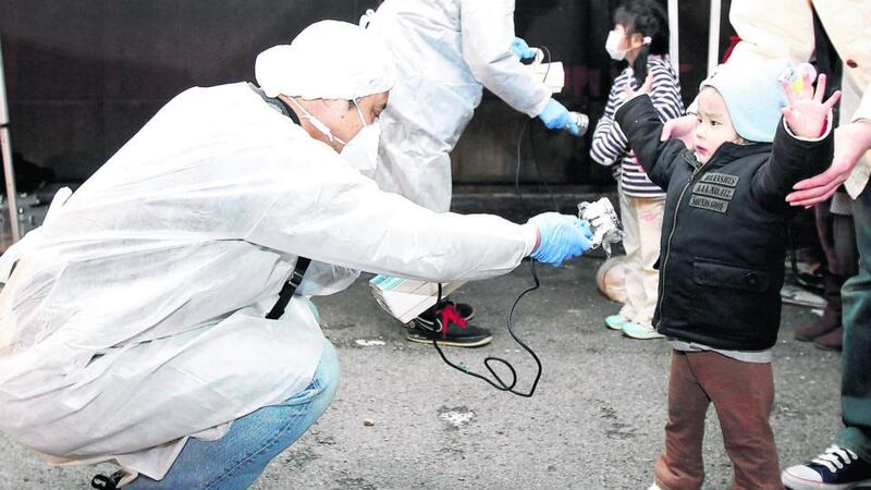 Officials in protective gear check for signs of radiation on children who came from the evacuation area near the Fukushima Daini nuclear plant in Koriyama, in March 2011. Photograph: Kim Kyung-Hoon/Reuters