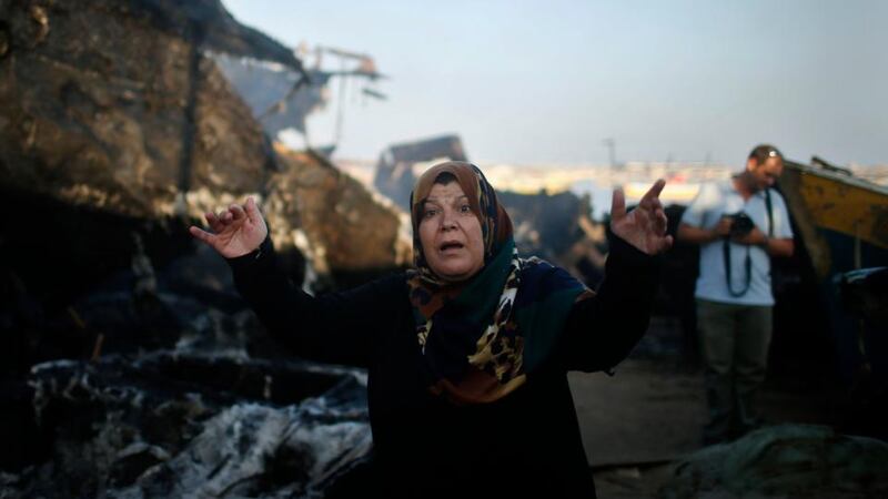 A Palestinian woman reacts in front of her son’s boat, which police say was damaged in a fire that started following an Israeli naval strike, at the seaport of Gaza City. Photograph: Mohammed Salem/Reuters