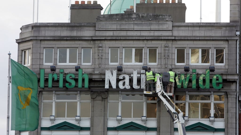 Workmen removing an Irish Nationwide Building Society sign overlooking O'Connell Bridge in Dublin