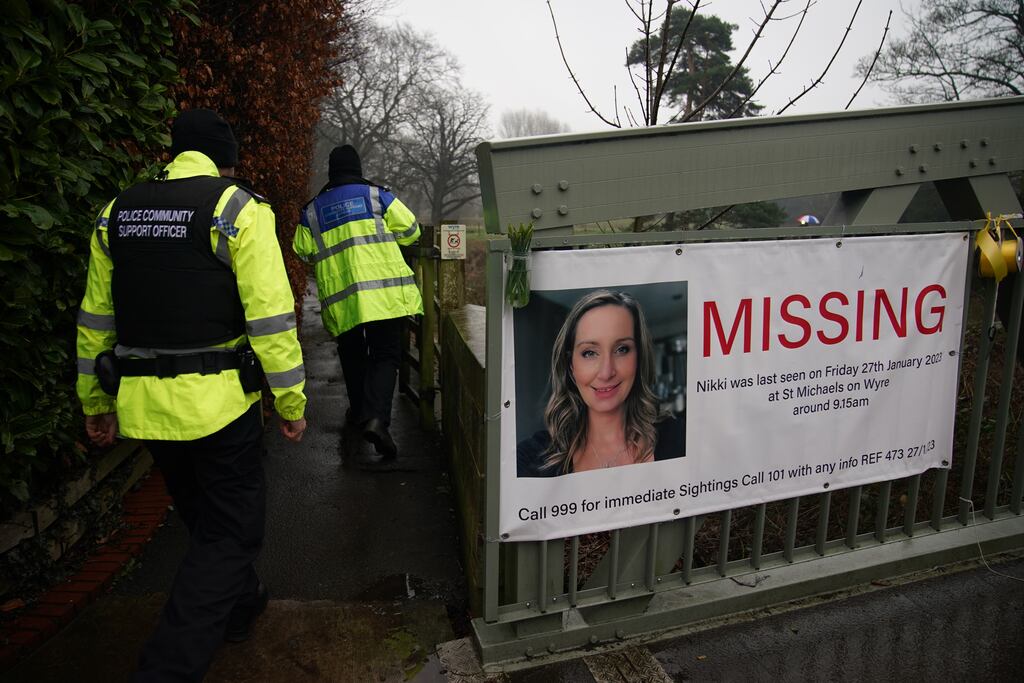 Police officers walk past a missing person appeal poster for Nicola Bulley tied to a bridge over the River Wyre. Photograph: PA