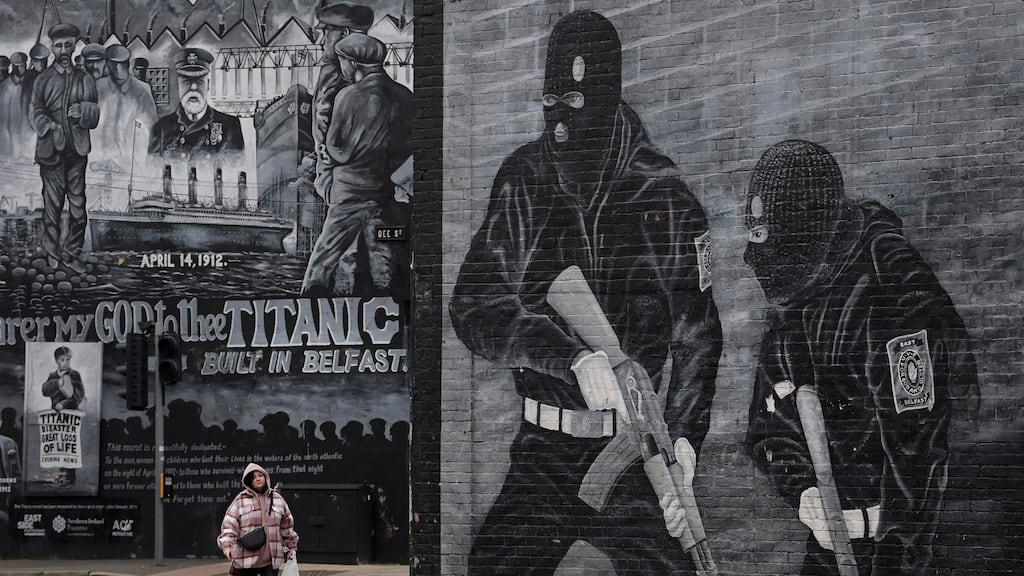 A woman walks past a Loyalist paramilitary mural on the Newtownards road in Belfast. An inquiry into the effect of paramilitarism on society heard that these groups  do prey on communities and  commit crime,  but in some instances  are seen as protecting the community as well. Photograph: Charles McQuillan/Getty