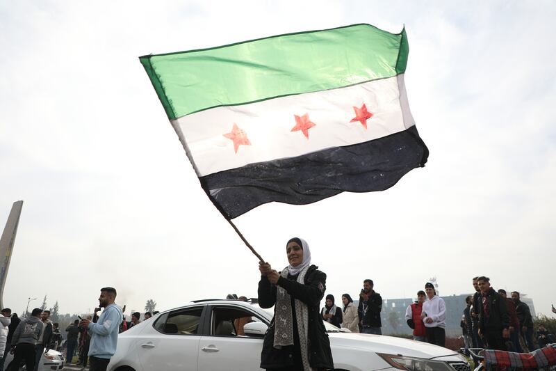 A woman waves the flag of the Syrian rebels as people gather to celebrate the fall of the government, in Umayyad Square in Damascus. Photograph: Ali Haj Suleiman/Getty Images