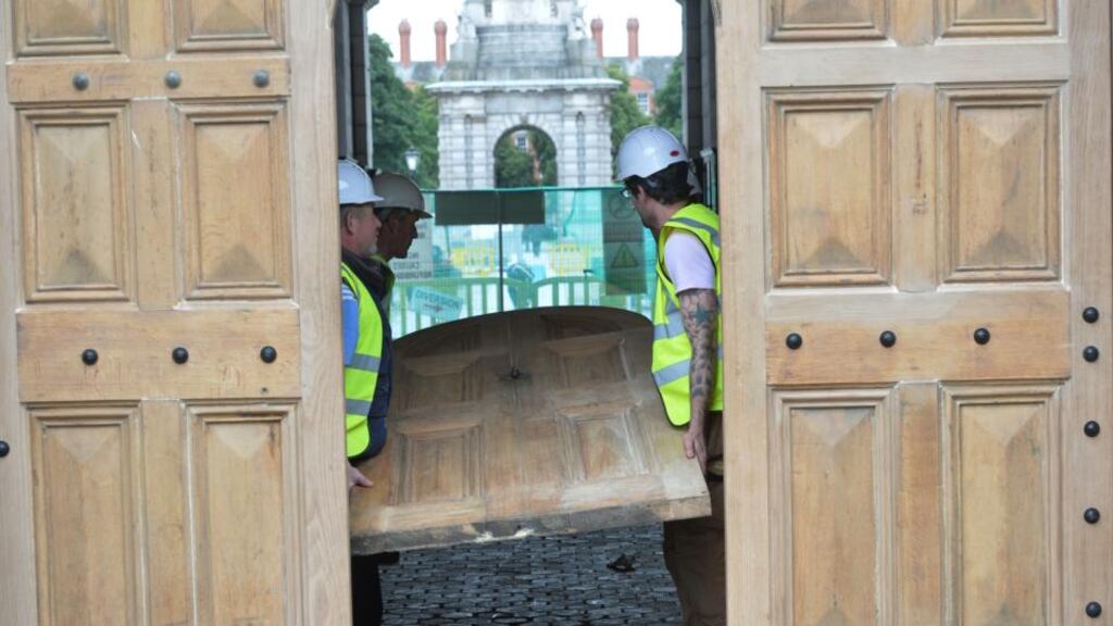 A newly restored front gate being reinstated at Trinity College Dublin by workmen in April 2014. Photograph: Alan Betson