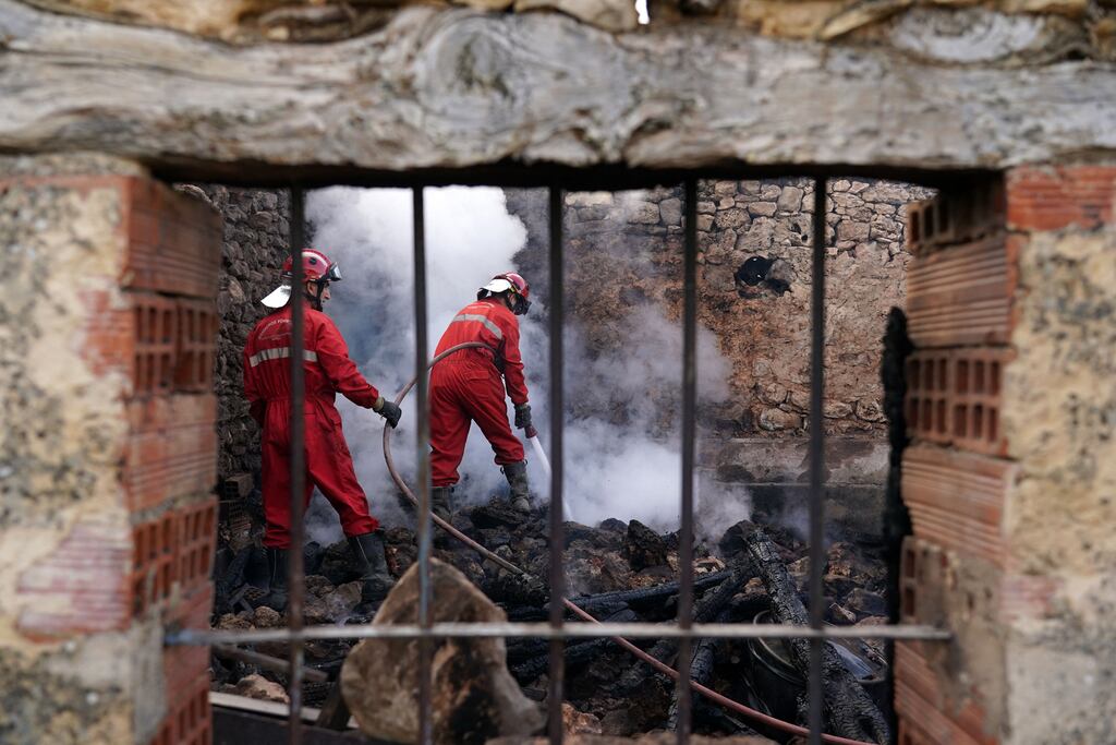 Firefighters douse smouldering rubble in a burnt-out house after a wildfire in the Valle del Arlanza, near Burgos in Spain during a heatwave in July. Photograph: Cesar Manso/Getty Images