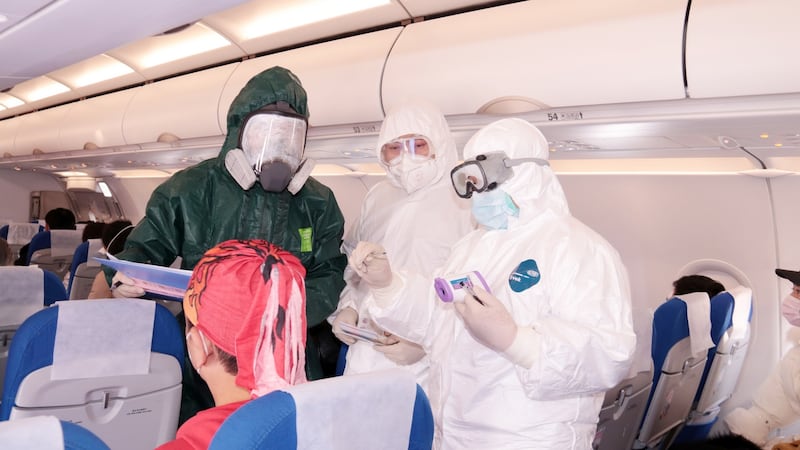 Police and medical personnel take temperature tests of passengers on board an airplane at the airport in Zhoushan City, Zhejiang Province on Tuesday. Photograph: EPA