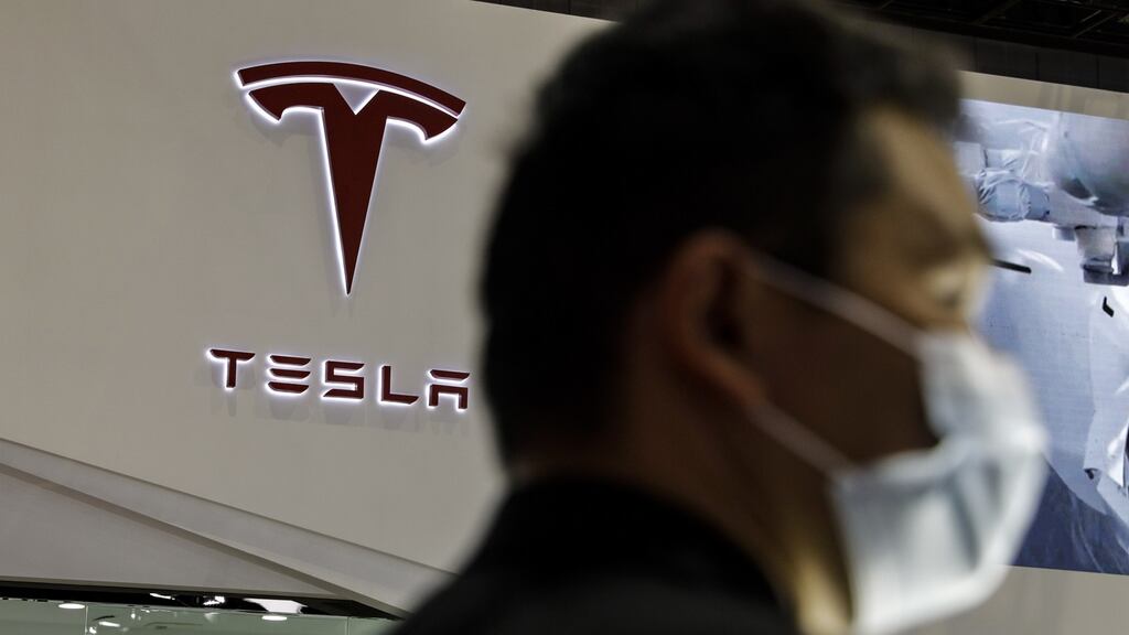 A visitor wearing a protective mask walk past the Tesla logo at the Auto Shanghai 2021 show in Shanghai, China, on Monday. Photograph: Qilai Shen/Bloomberg