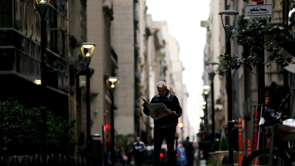 A man reads a newspaper as he walks in Buenos Aires’ financial district. Photograph: Reuters/Marcos Brindicci