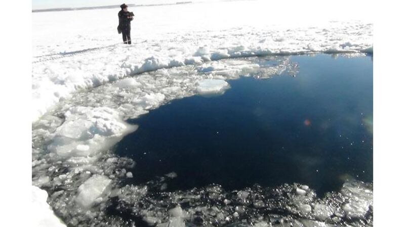 A Russian policeman works near an ice hole, said by the interior ministry department for Chelyabinsk region to be the point of impact of a meteor. Photograph: Chelyabinsk region interior ministry/Reuters