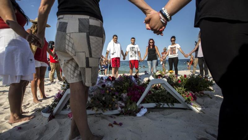 People hold hands as they pray in a circle around bouquets of flowers laid in tribute on the beach of the Imperial Marhaba resort, which was attacked by a gunman, in Sousse, Tunisia, June 28th, 2015. Photograph: Zohra Bensemra/Reuters