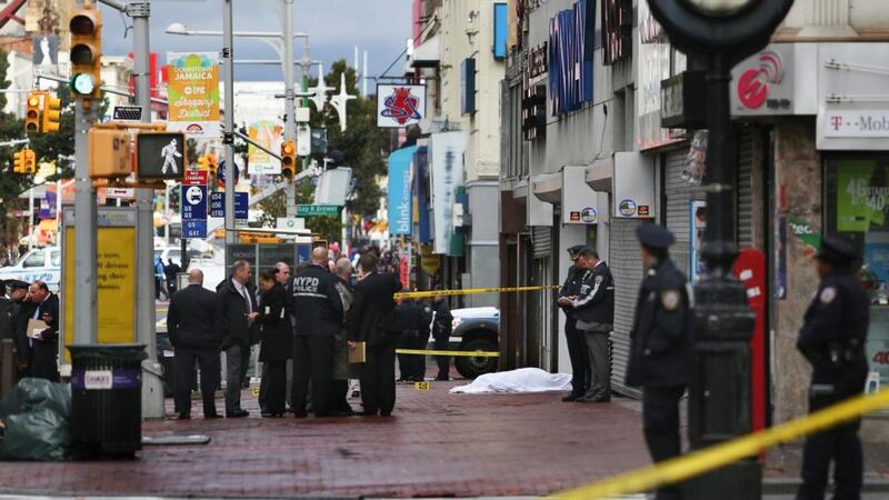 New York police officers and investigators stand around the body of a man who was killed after he attacked police with a hatchet yesterday. Photograph: Kirsten Luce/The New York Times