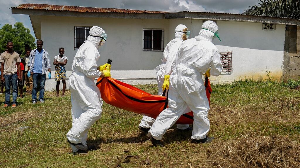 A Liberian Red Cross burial team retrieves the body of a suspected victim of Ebola in Banjor, on the outskirts of Monrovia. Photograph: EPA/Ahmed Jallanzo